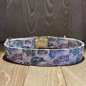 May include: A white dog collar with a silver buckle and a pattern of blue, green, and purple cars.