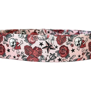 May include: Pink fabric with a repeating pattern of red roses, skulls, and nautical stars. The fabric is suitable for crafting projects like headbands, scrunchies, and hair bows.