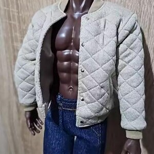 May include: A dark-skinned articulated doll figure wearing a beige quilted bomber jacket with a snap-button front closure and dark blue denim jeans. The jacket features a textured diamond-patterned fabric and ribbed cuffs, worn open over the torso.