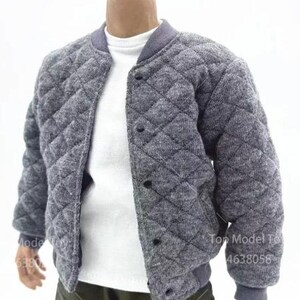 May include: A grey quilted bomber jacket with a diamond pattern, a ribbed collar, and black snap buttons. The jacket is worn over a plain white t-shirt. The outfit is completed with olive green cargo trousers featuring visible stitching and side pockets.
