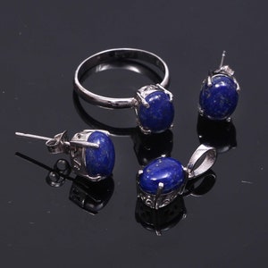 May include: A silver ring, earrings, and pendant necklace set with oval-shaped blue lapis lazuli stones.