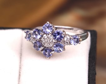 May include: A silver ring with a cluster of purple gemstones and small white diamonds.