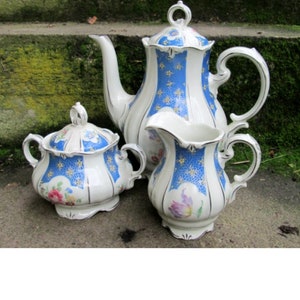 Könnte beinhalten: Ein antikes Porzellan-Tee-Set mit einem blauen und weißen Blumenmuster. Das Set enthält eine Teekanne, eine Milchkännchen und eine Zuckerdose.