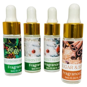 May include: Four small glass fragrance oil bottles with white droppers and gold caps. The labels read "Hollyberry & Fragrance", "Christmas Fragrance", "Christmas Fragrance", and "Sugar & Spice Fragrance". Each bottle contains 5ml (0.16 fl oz).