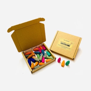 May include: A box of colourful backflow incense cones in a variety of colours, including pink, blue, green, orange, and yellow. The box is labelled "Backflow Cones Assorted Mix".