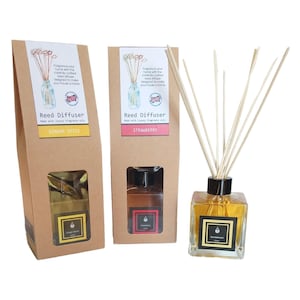 May include: Three reed diffusers in glass bottles with wooden reeds. Two are in brown cardboard boxes with labels that read "Ginger Spice" and "Strawberry." The third diffuser is visible with a "Sandalwood" label. The text "Fragrance your home" is visible.