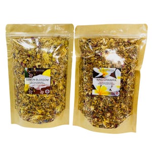 May include: Two clear pouches filled with dried botanicals. One is labelled "Lemon Blossom" and the other "Nag Champa". Both are sealed and set against a brown paper background. The labels include floral designs and the Union Jack.
