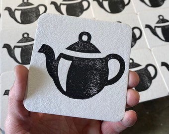 May include: A set of black and white coasters featuring a simple design of a teapot. The coasters are made of a thick, absorbent material and are perfect for protecting surfaces from spills.