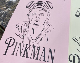 May include: Pink and white stencil with a black line drawing of a person wearing a gas mask and the word "PINKMAN" printed below the image.