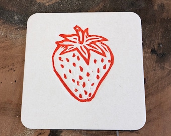 May include: Square, white coaster with a hand-drawn red strawberry design. The strawberry has a detailed outline and seed pattern. The coaster is made of a thick, absorbent material, perfect for protecting surfaces from drink condensation.