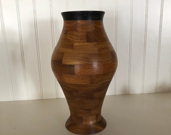May include: A wooden vase with a dark brown rim, made of small pieces of wood arranged in a geometric pattern.