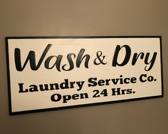 May include: Black and white sign with the text "Wash & Dry Laundry Service Co. Open 24 Hrs."