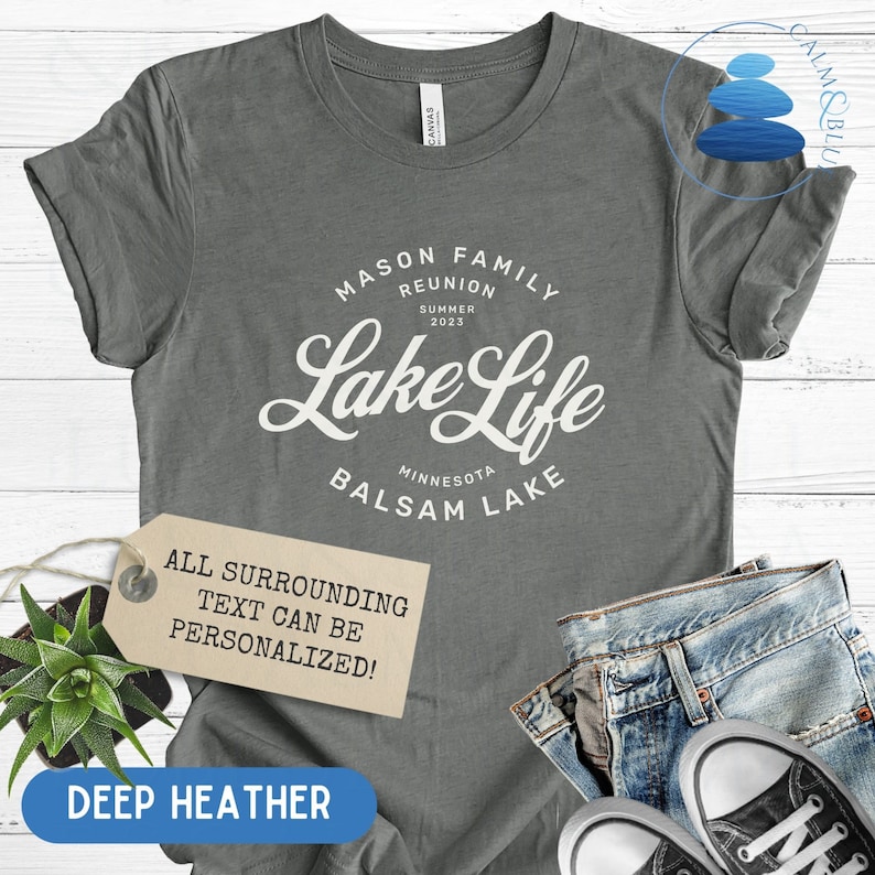 K&ouml;nnte beinhalten: Ein heidefarbenes T-Shirt mit wei&szlig;em Text, der "Mason Family Reunion Summer 2023 Lake Life Minnesota Balsam Lake" lautet. Der Text ist in einer Vintage-Schriftart gehalten. Der Text "All surrounding text can be personalized!" befindet sich auf einem braunen Etikett.