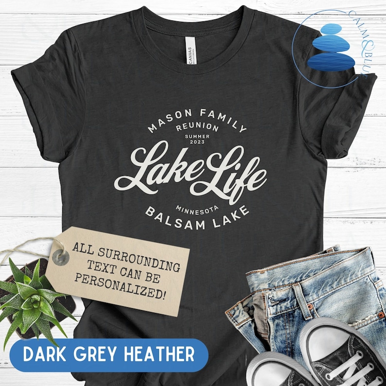 K&ouml;nnte beinhalten: Dunkelgraues T-Shirt aus Heather-Material mit wei&szlig;em Text, der "Mason Family Reunion Summer 2023 Lake Life Minnesota Balsam Lake" lautet. Der Text ist in einer Vintage-Schriftart gehalten. Ein Etikett ist am T-Shirt befestigt, auf dem "Der gesamte umgebende Text kann personalisiert werden!" steht.