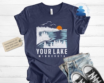 May include: A navy blue t-shirt with a white graphic of a lake scene with a sunset. The text "YOUR LAKE MINNESOTA" is printed below the graphic.