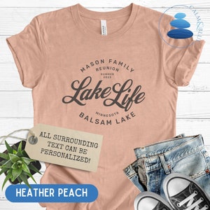 K&ouml;nnte beinhalten: Ein T-Shirt in der Farbe Heide-Pfirsich mit dem Text "MASON FAMILY REUNION SUMMER 2023 Lake Life MINNESOTA BALSAM LAKE" in Schwarz. Der Text "ALL SURROUNDING TEXT CAN BE PERSONALIZED!" befindet sich auf einem braunen Etikett.
