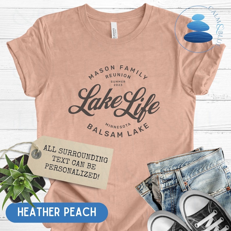 K&ouml;nnte beinhalten: Ein T-Shirt in der Farbe Heide-Pfirsich mit dem Text "MASON FAMILY REUNION SUMMER 2023 Lake Life MINNESOTA BALSAM LAKE" in Schwarz. Der Text "ALL SURROUNDING TEXT CAN BE PERSONALIZED!" befindet sich auf einem braunen Etikett.