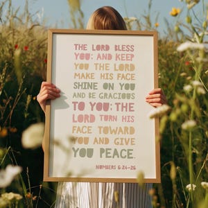 Puede incluir: Un cartel enmarcado con el texto "THE LORD BLESS YOU: AND KEEP YOU THE LORD MAKE HIS FACE SHINE ON YOU AND BE GRACIOUS TO YOU: THE LORD TURN HIS FACE TOWARD YOU AND GIVE YOU PEACE. NUMBERS 6:24-26". El marco es marrón claro.
