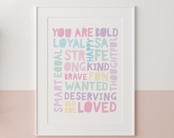 Può includere: Una stampa incorniciata bianca con una nuvola di parole colorata che recita "You are bold, loyal, smart, equal, strong, kind, brave, fun, wanted, deserving, one loved." Le parole sono disposte in una colonna verticale e sono di diversi colori, tra cui rosa, blu, verde e giallo.