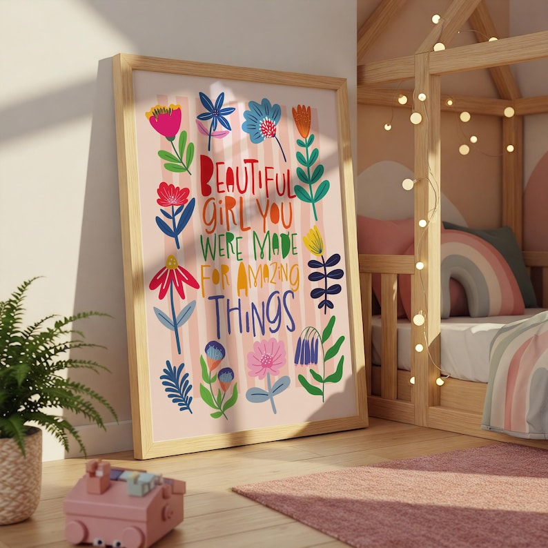 May include: A framed art print with the words "BEAUTIFUL GIRL YOU WERE MADE FOR AMAZING THINGS" in colorful letters. The print features floral illustrations in pink, red, blue, and yellow. The frame is made of light-colored wood.