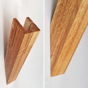 May include: A wooden shelf bracket with a U-shaped design. The bracket is made of light brown wood with a natural grain pattern.