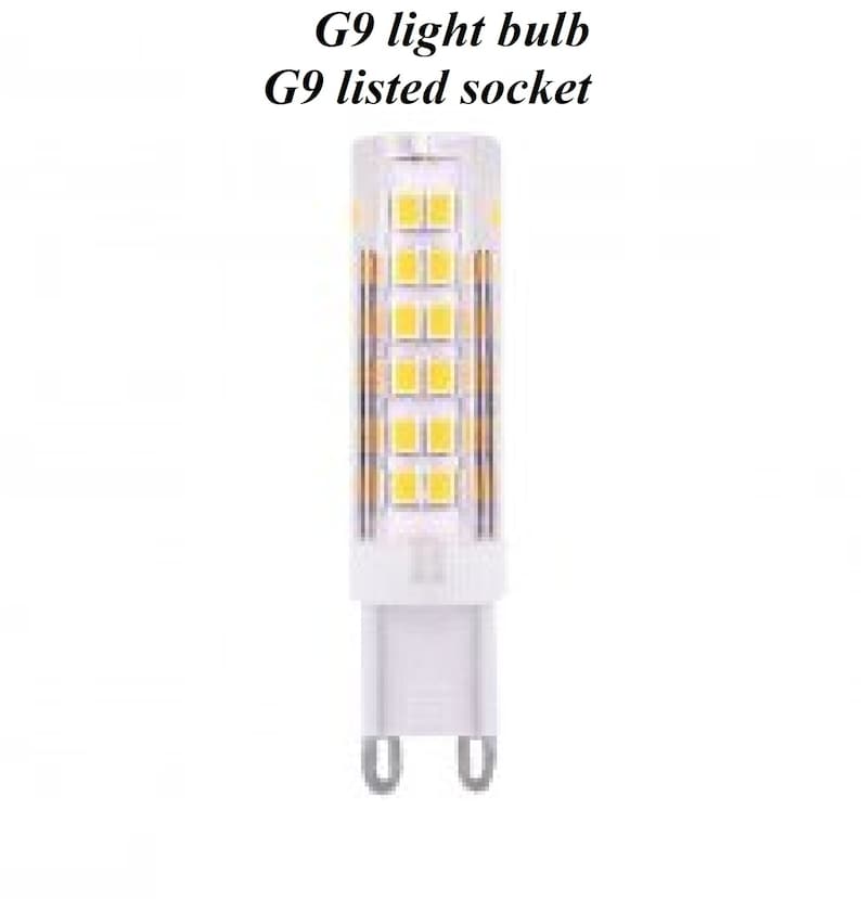 May include: A white G9 light bulb with a clear glass cover and a white plastic base. The bulb has a grid of small, yellow LED lights inside. The text "G9 light bulb" and "G9 listed socket" is printed above the bulb.