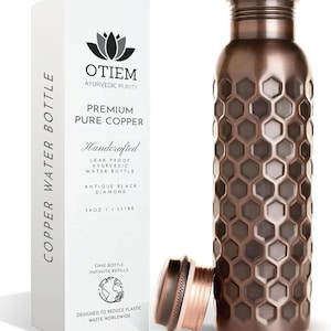 May include: An antique black diamond copper water bottle with a honeycomb design, next to its packaging. The bottle is 34 oz / 1 liter and is designed to reduce plastic waste. The packaging reads "OTIEM Ayurvedic Purity, Premium Pure Copper, Handcrafted".