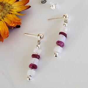 Puede incluir: Pendientes de plata con una pila de cuentas de piedras preciosas blancas y rosadas. Los pendientes están marcados con 925, lo que indica que son de plata de ley.