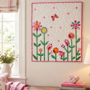 Könnte beinhalten: Ein rechteckiger Wandbehang aus Stoff mit cremefarbenem Hintergrund und aufwendigen Steppmustern. Das Design zeigt verschiedene bunte Stoffblumen mit grünen Stielen und Blättern, akzentuiert durch einen kleinen Schmetterling und rosa Punkte.