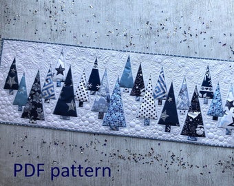 May include: A quilted table runner featuring a row of stylized Christmas trees in various shades of blue and white. The trees are made from patterned fabrics, including polka dots and stars. The text "PDF pattern" is visible.