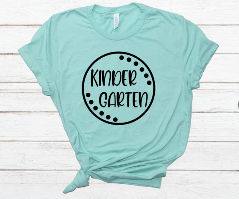 May include: A light blue t-shirt with a black circle design that says "Kindergarten" in a white font.