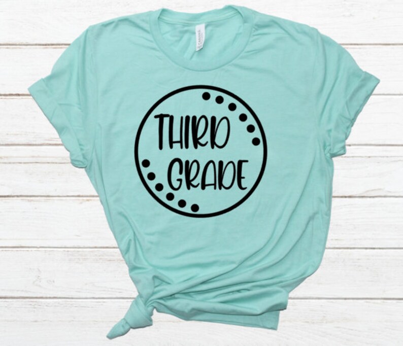 May include: A turquoise t-shirt with a black circle design that says "Third Grade" in a white font.