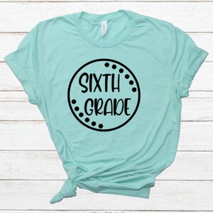 May include: A turquoise t-shirt with a black circle design that says "SIXTH GRADE" in a white font.