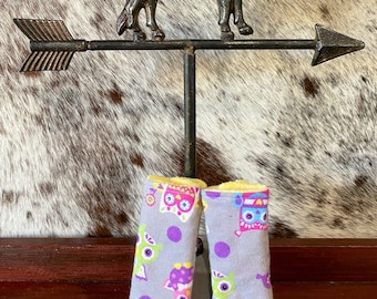 May include: Two purple and gray fabric car seat armrest covers with a yellow border and a pattern of colorful owls and purple polka dots.