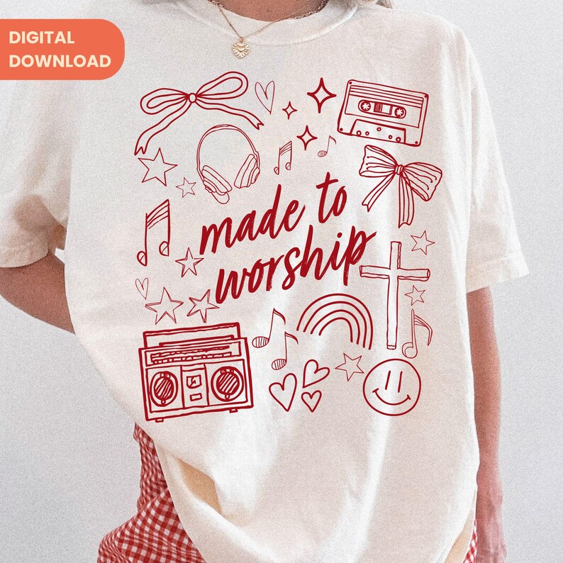 Op de afbeelding: Cr&egrave;mekleurig T-shirt met een rood grafisch ontwerp. Het ontwerp bevat een kruis, muzieknoten, een regenboog, een cassettebandje, een boombox en de woorden "made to worship". Het shirt heeft korte mouwen.