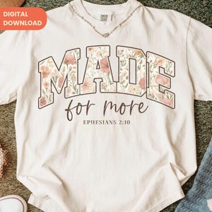 May include: Cream-colored t-shirt with the words "MADE" and "for more" in a floral design. The text "Ephesians 2:10" is printed below. The shirt has a relaxed fit and short sleeves. A digital download tag is in the upper left corner.
