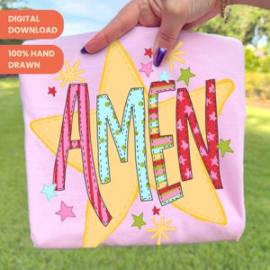 Op de afbeelding: Een roze t-shirt met het woord "AMEN" in kleurrijke, patroonletters. Het woord staat tegen een gele sterrenuitbarsting, met extra sterrenafbeeldingen verspreid. Het shirt heeft ook de tekst "DIGITALE DOWNLOAD" en "100% HANDGETEKEND".