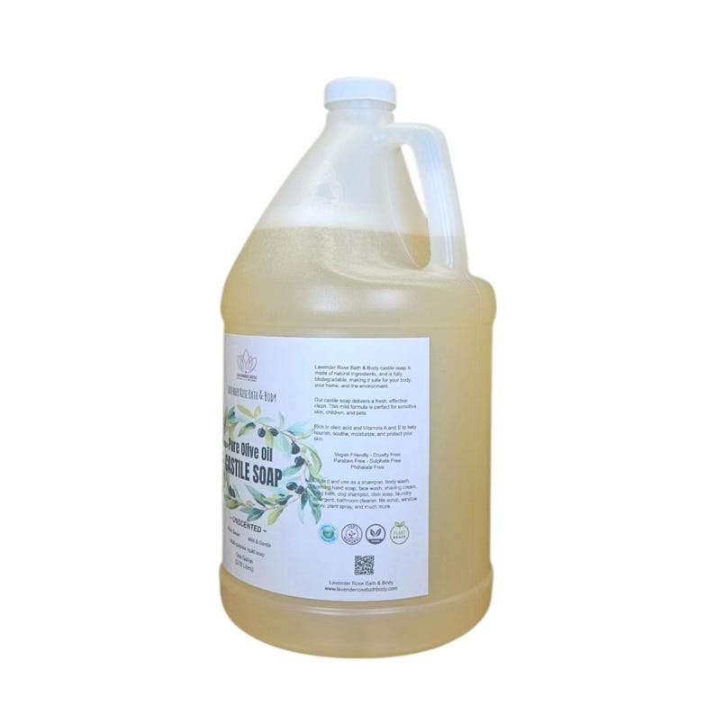 Puede incluir: Un gran recipiente de pl&aacute;stico transparente de jab&oacute;n l&iacute;quido con tapa y asa blancas. La etiqueta dice "Pure Olive Oil Castile Soap" con una ilustraci&oacute;n de rama de olivo. El jab&oacute;n no tiene perfume y es apto para veganos. El recipiente est&aacute; lleno de un l&iacute;quido amarillo claro.