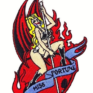 May include: Embroidered patch featuring a woman with wings and a trident, holding a pole with a banner that reads "Miss Fortune". The woman is wearing a black bikini and boots, and is surrounded by flames.