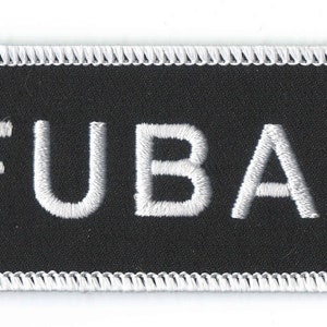 May include: A black rectangular patch with white embroidered text reading "FUBAR". The patch has a white stitched border. A US quarter is next to the patch for size comparison.
