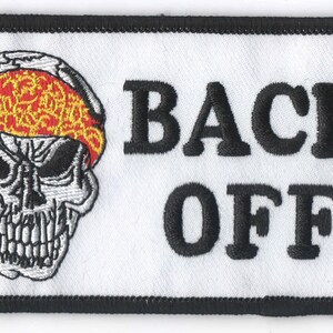 May include: White embroidered patch with a black border. The patch features a skull with a red and yellow bandana and the text "BACK OFF".