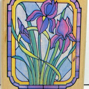 May include: A wooden stamp with a stained glass design of purple irises in a yellow and purple frame.