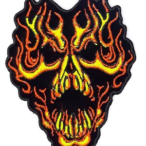 May include: Embroidered patch of a black skull with yellow and orange flames. The skull is outlined in black and the flames are detailed with yellow and orange thread.