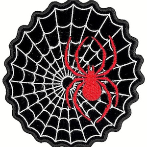 May include: Black and white embroidered spider web with a red spider in the center.