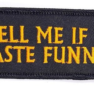 May include: Black embroidered patch with yellow stitching that reads "TELL ME IF I TASTE FUNNY".
