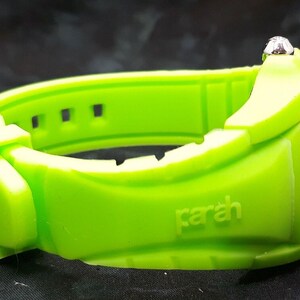 May include: A bright green wristwatch with a silver face and a silicone band. The band has the word "parah" embossed on it.