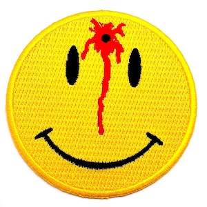 May include: Yellow embroidered patch featuring a smiley face with black eyes and a curved mouth. A red blood-like stain emanates from the top of the smiley face. The patch has a stitched border.