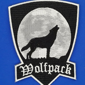 May include: Black and white embroidered patch with a wolf howling at the moon. The patch has a white border and the text "Wolfpack" in a gothic font.