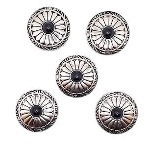 May include: Five silver-toned metal buttons with a black center and a decorative floral design. The buttons have a raised, textured surface.