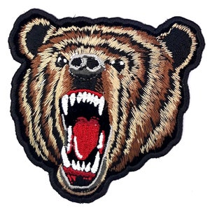 May include: Embroidered patch of a brown bear with a black nose and open mouth showing sharp teeth. The bear's fur is detailed with brown and beige stitching.